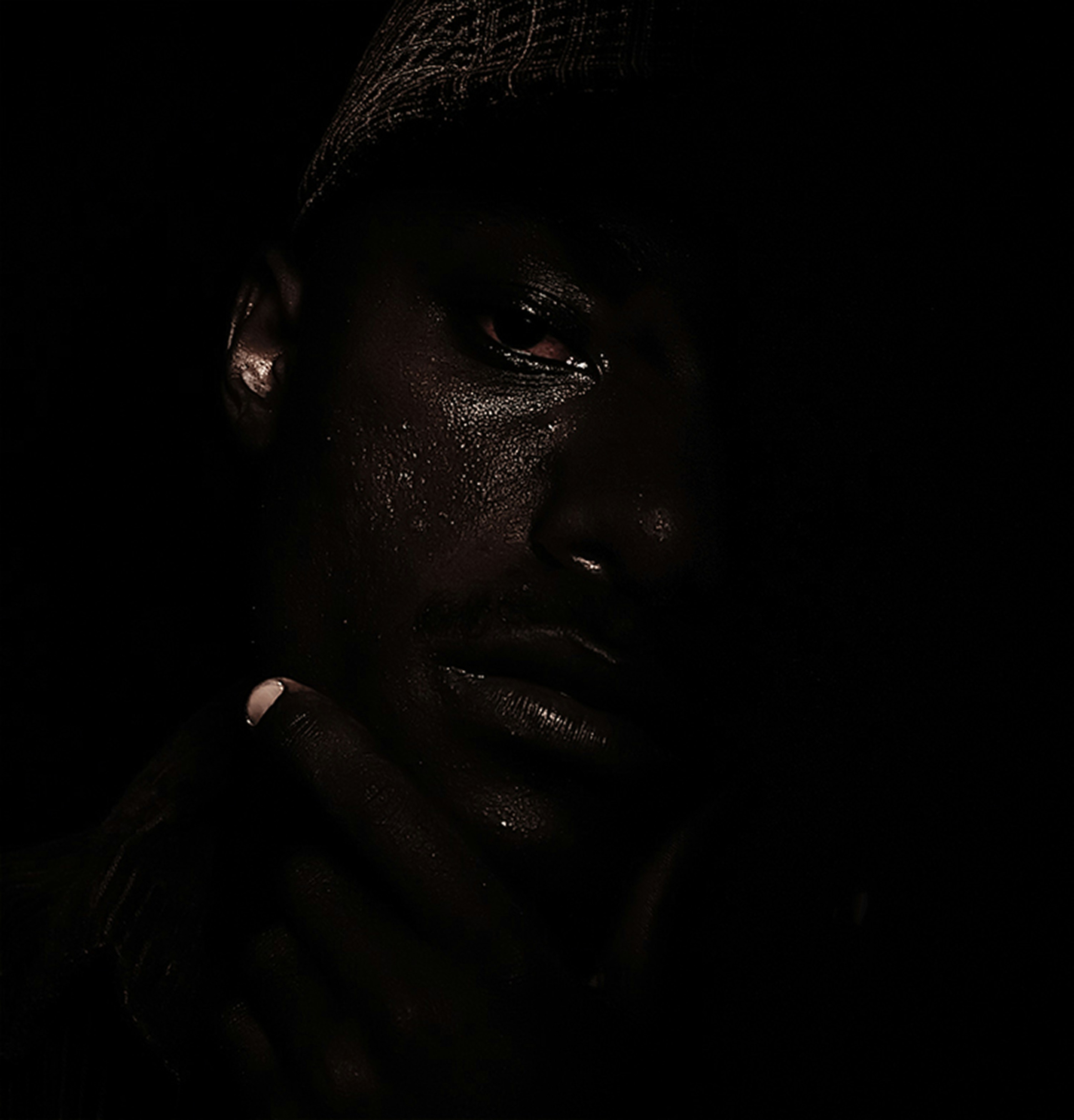 a man in a dark room with his hand on his face